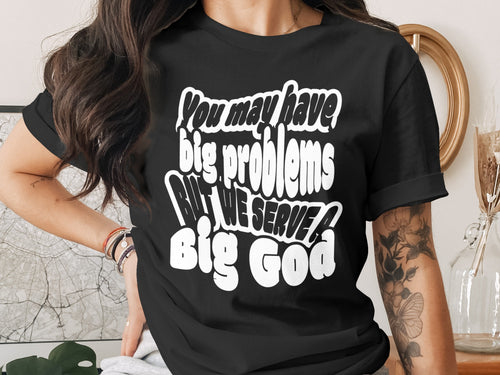 Black t-shirt with white text reading "You may have big problems BUT WE SERVE A Big God".