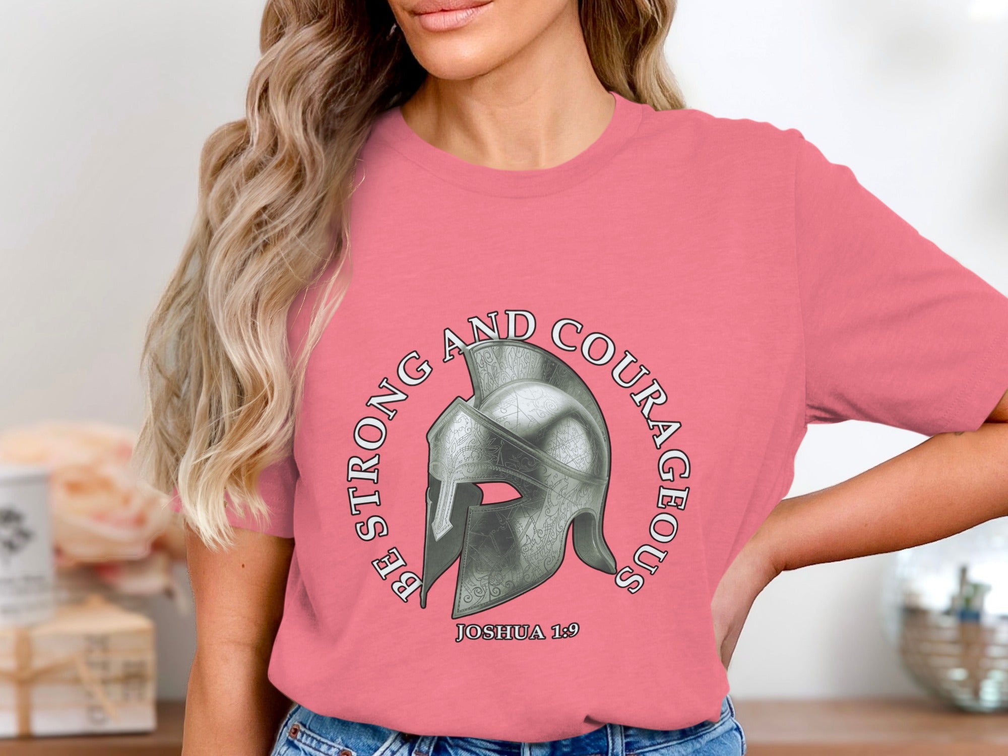 Pink t-shirt with Roman helmet and text "BE STRONG AND COURAGEOUS" and "JOSHUA 1:9".