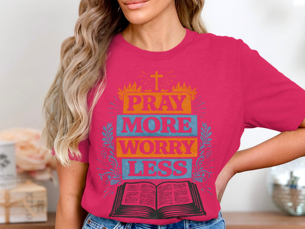 Pink t-shirt with "PRAY MORE WORRY LESS" text above an open book and cross.